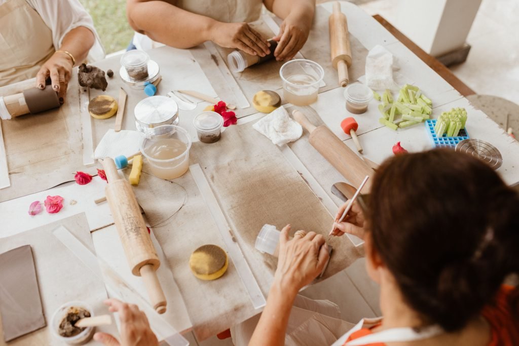 Plusieurs paires de mains façonnent l'argile autour d'une grande table d'atelier