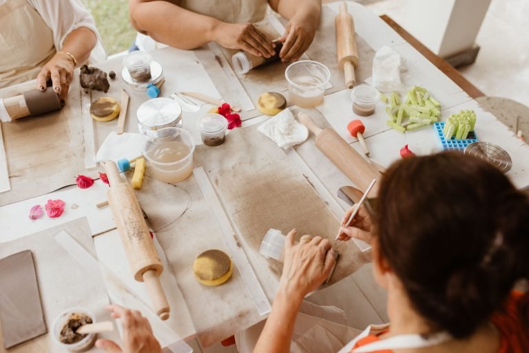 Plusieurs paires de mains façonnent l'argile autour d'une grande table d'atelier